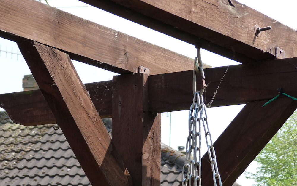 Copyright image: A pergola swing bench attached to rafters with chain and bolts.