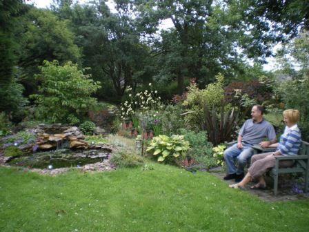 Copyright image: Natural pond with love seat and plants as part of a garden makeover.