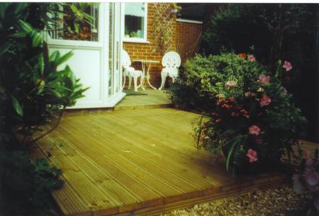 Copyright image: Split level decking with white metal garden furniture.