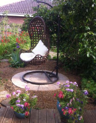 Copyright image: An interesting garden feature with a hanging chair and patio circle.