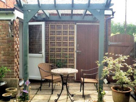 Copyright image: Kevin's attached lean-to pergola with a patio set and climbing plants.